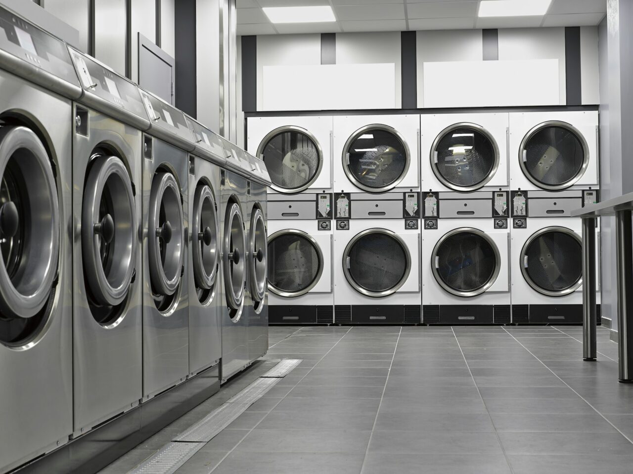 row of industrial washing machines in a public laundromat